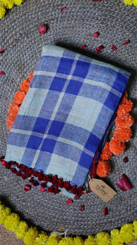 Blue checkered fabric with a tag on a textured surface with flowers and petals.