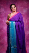 Woman wearing a purple saree with a pink blouse against a pink background