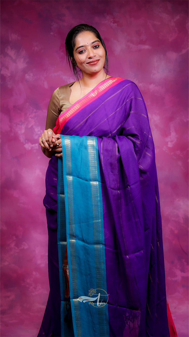 Woman wearing a purple saree with a pink blouse against a pink background