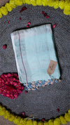 Light blue fabric with a brand tag on a textured surface with decorative elements
