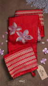 Red fabric with floral embroidery on a brown surface with decorative elements.