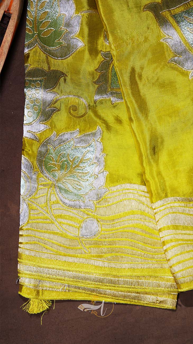 Yellow fabric with silver embroidery on a brown background