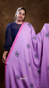 Woman wearing a purple saree with green and black patterns against a brown background