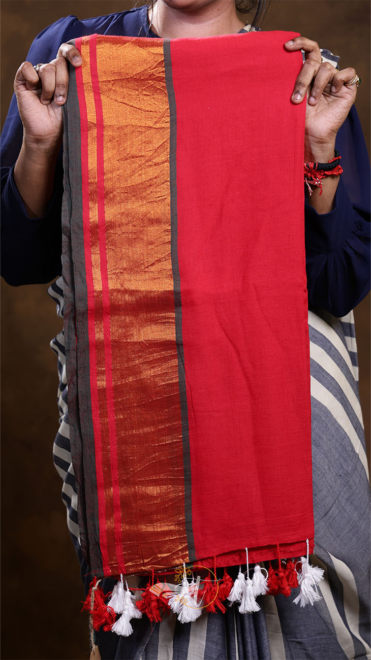 Red and orange fabric with tassels held by a person against a brown background