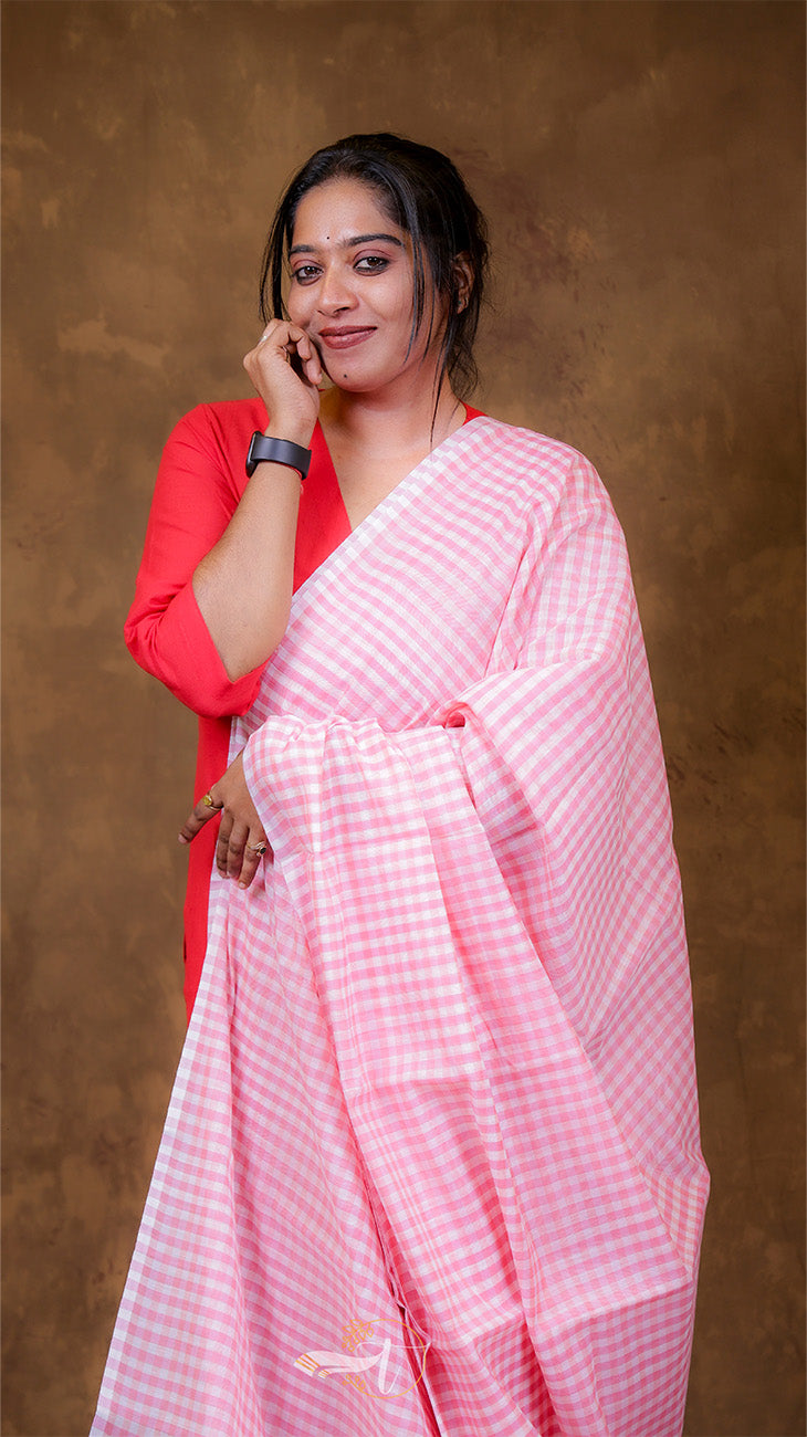 Woman wearing a pink saree with a red blouse against a brown background