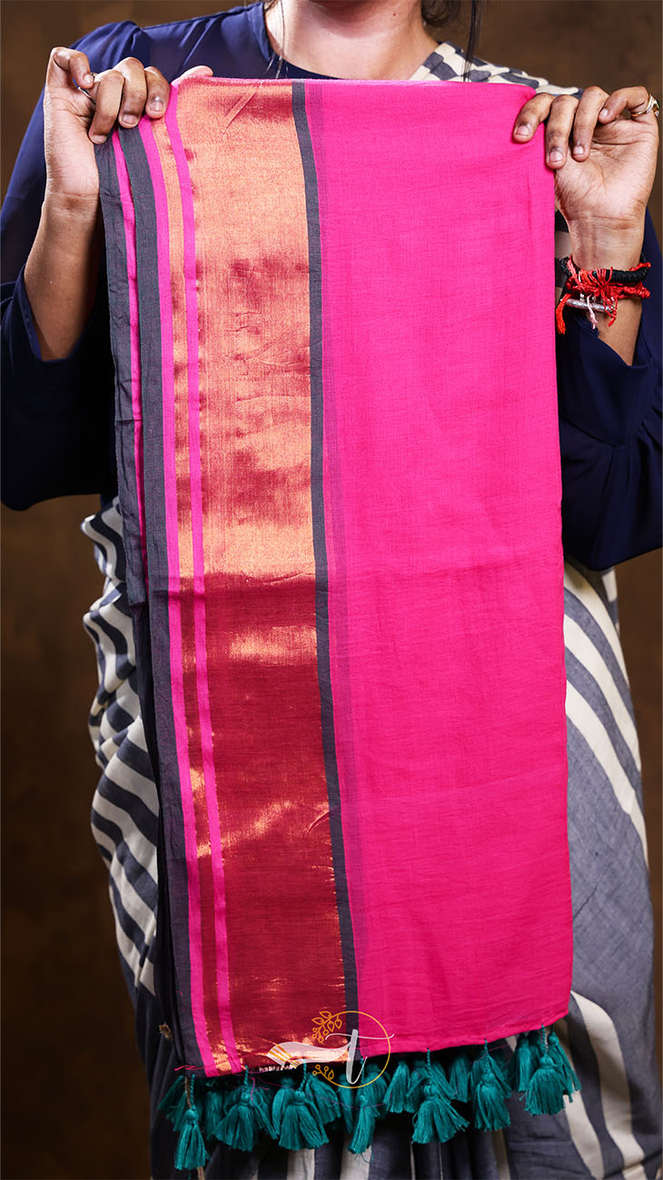 Person holding a pink fabric with a black border and green tassels.
