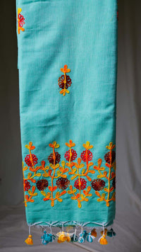 Turquoise fabric with colorful floral embroidery on a plain background