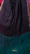 Dark fabric draped over a green surface with a brand logo in the corner.