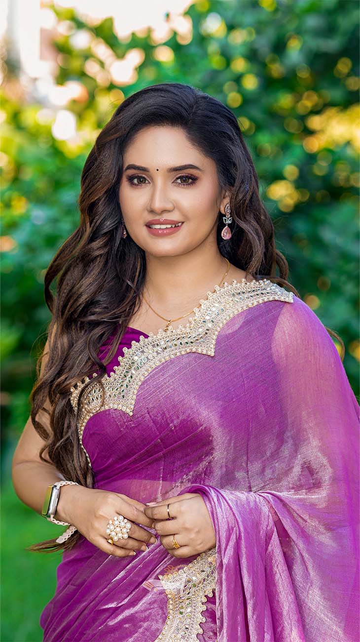 Woman in a purple saree with a blurred green background