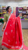 Woman holding a red saree with a pattern in a store setting