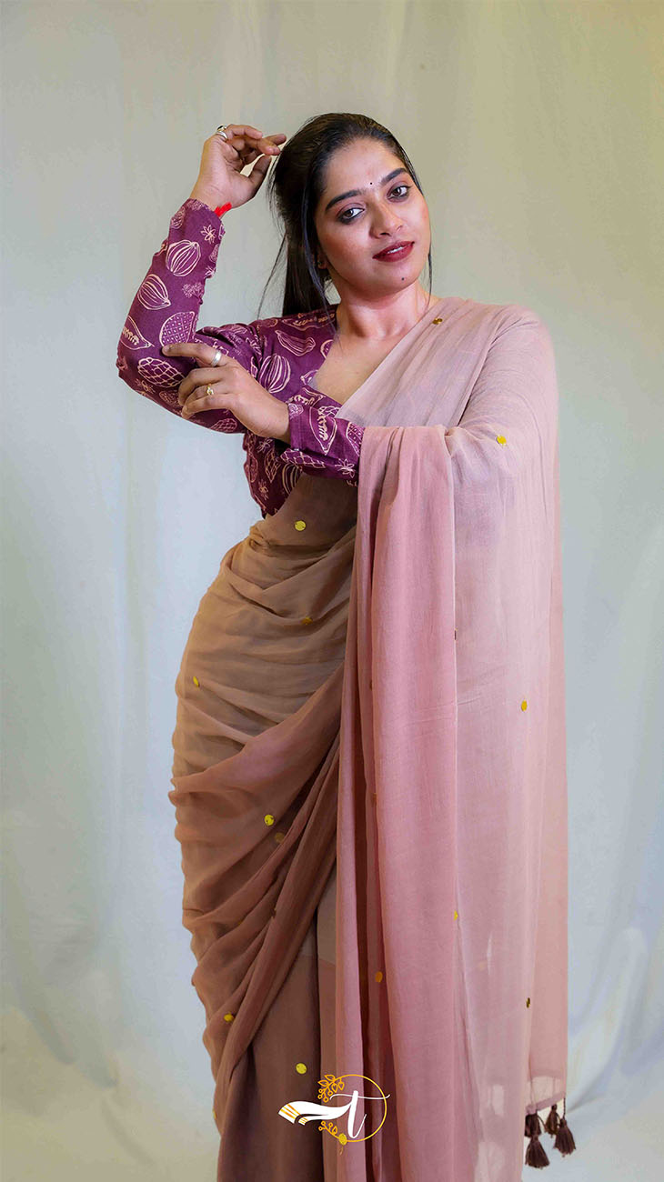 Woman wearing a brown saree with a pink blouse against a white background