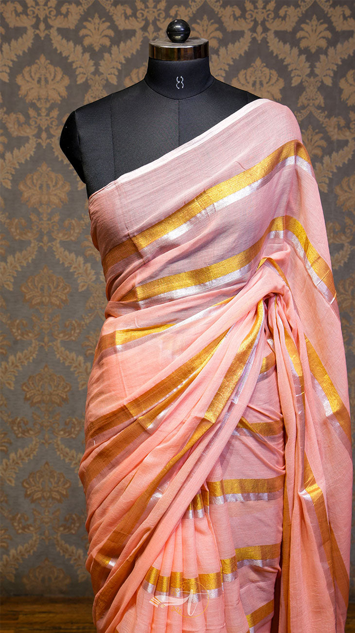 Pink saree with gold stripes on a mannequin against a patterned wall.