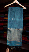 Blue saree with gold border on a hanger against a blurred fabric background