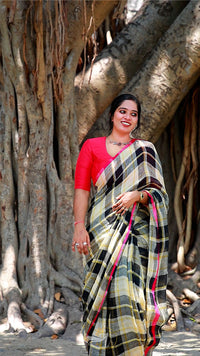 Woman in a colorful saree standing in front of a large tree with intricate root system.