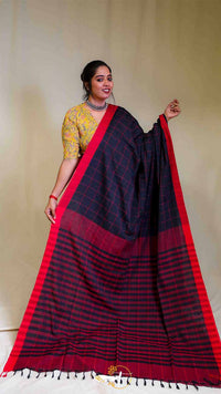 Woman wearing a black and red saree with a yellow blouse against a plain background