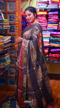 Woman in a colorful traditional outfit standing in front of a vibrant fabric display.