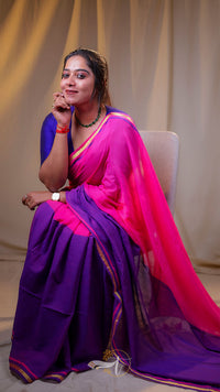 Woman wearing a vibrant purple and pink saree sitting on a chair.