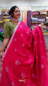 Woman holding a pink saree with a visible brand logo in a fabric store.