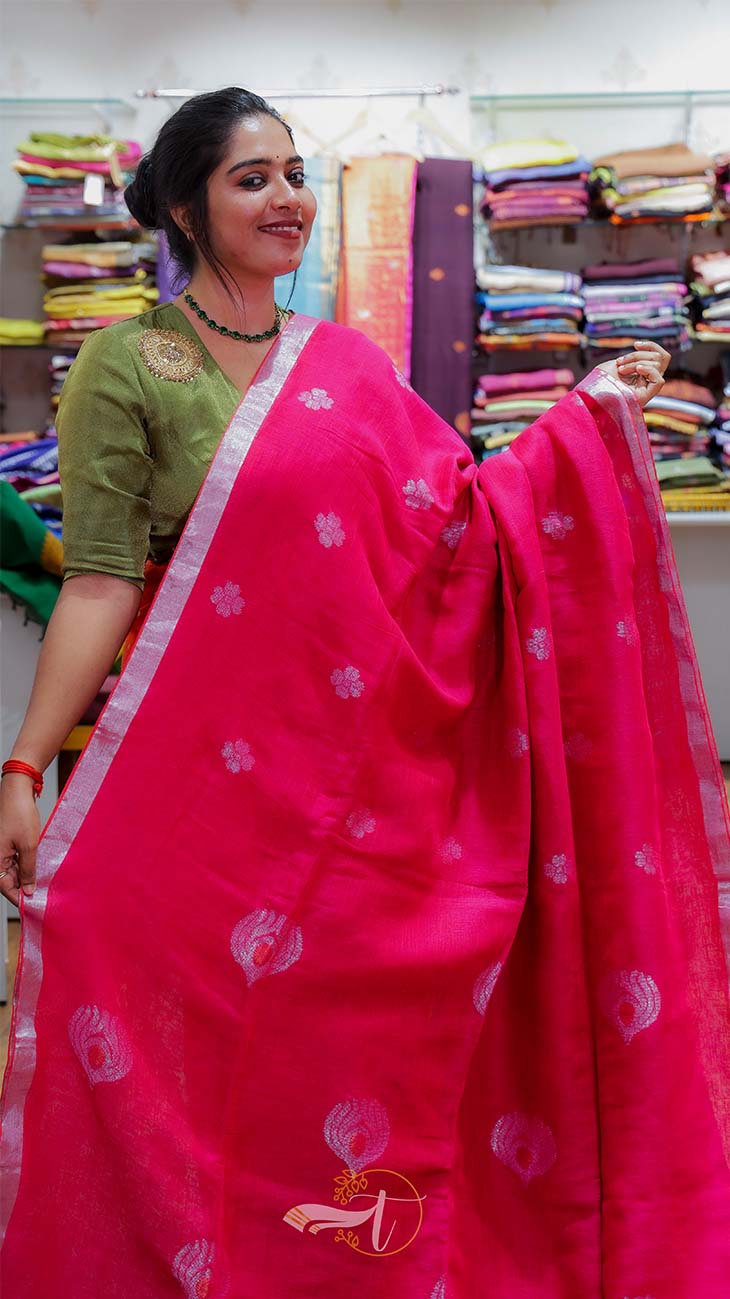 Woman holding a pink saree with a visible brand logo in a fabric store.
