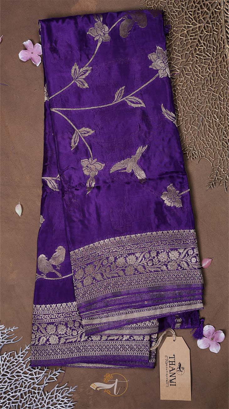 Purple fabric with silver floral and bird patterns on a brown background