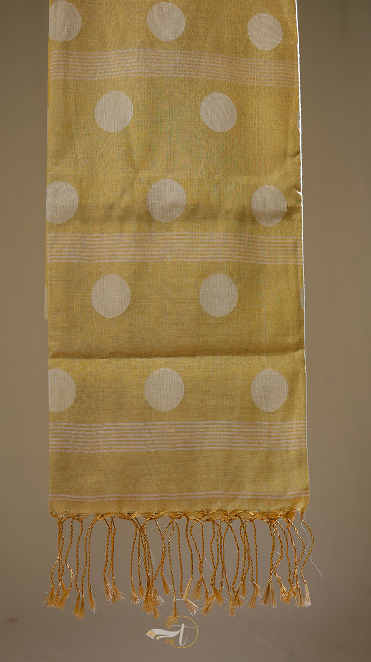 Yellow fabric with white circular patterns and fringes on a brown background
