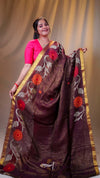 Woman wearing a brown saree with floral patterns and a pink blouse against a plain background
