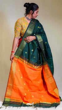 Woman wearing a green and orange saree with a plain background