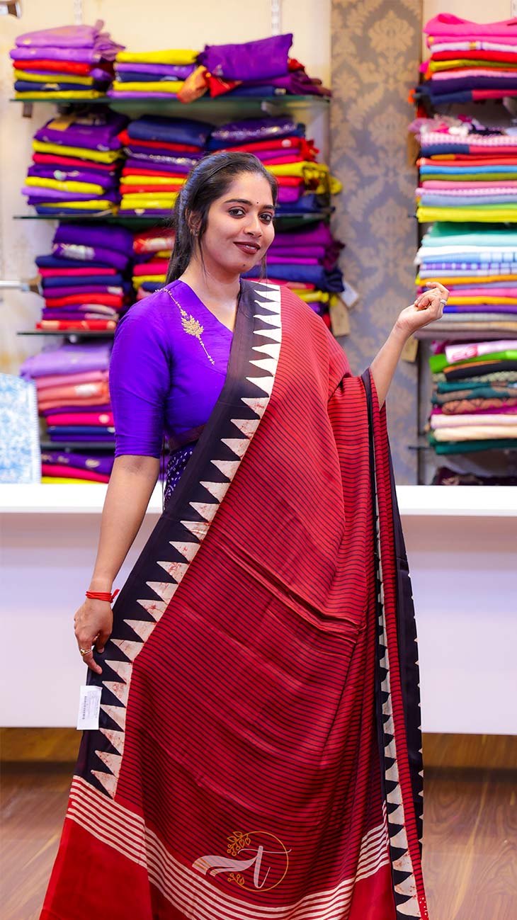 Woman wearing a red saree with a purple blouse in a fabric store.