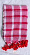 Red and white checkered scarf with red pom-poms on a light gray background