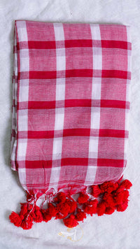 Red and white checkered scarf with red pom-poms on a light gray background
