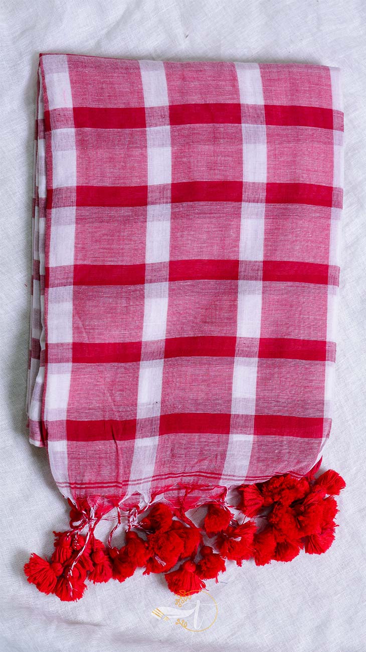Red and white checkered scarf with red pom-poms on a light gray background