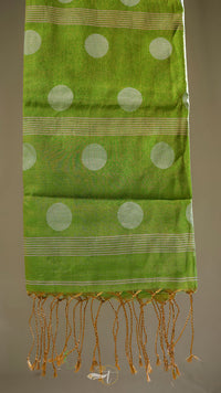 Green scarf with white polka dots and gold fringe on a neutral background