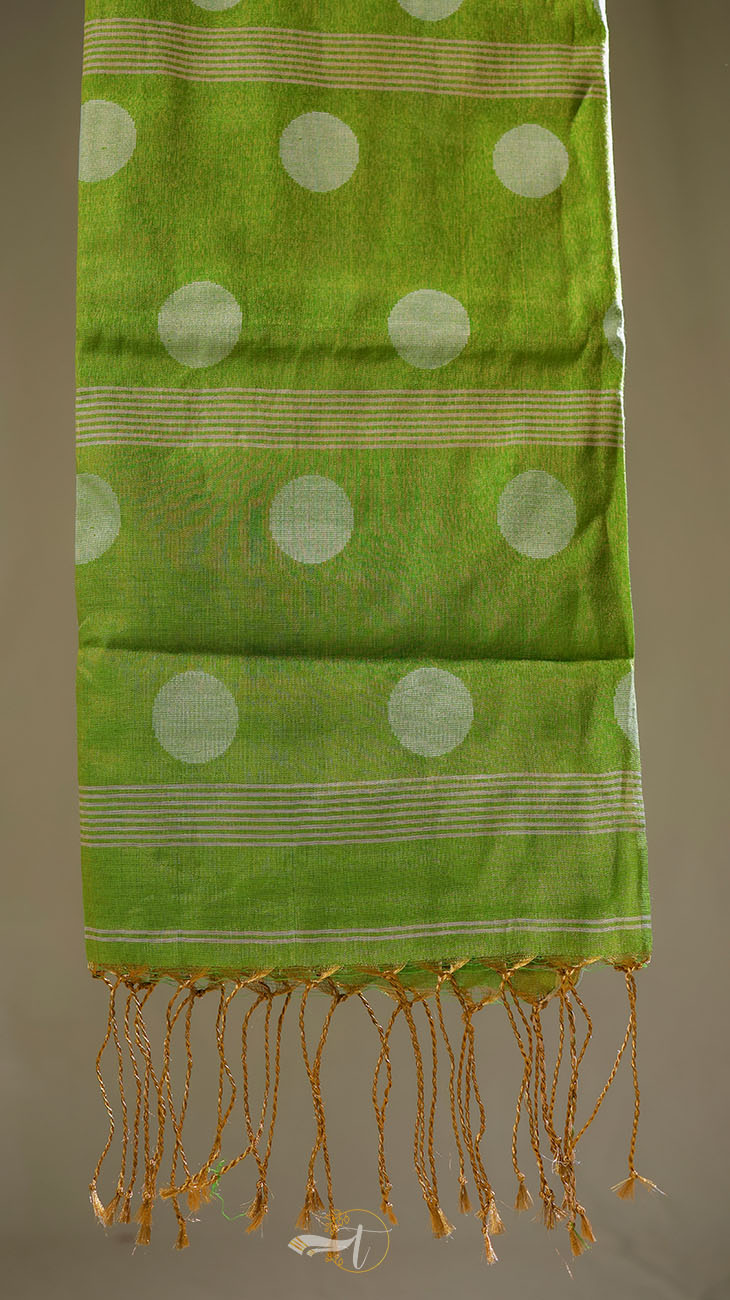 Green scarf with white polka dots and gold fringe on a neutral background