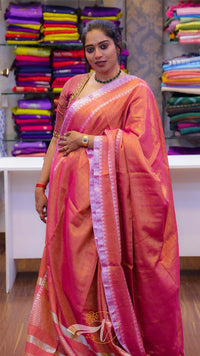 Woman wearing a traditional saree in a store setting with colorful fabrics in the background