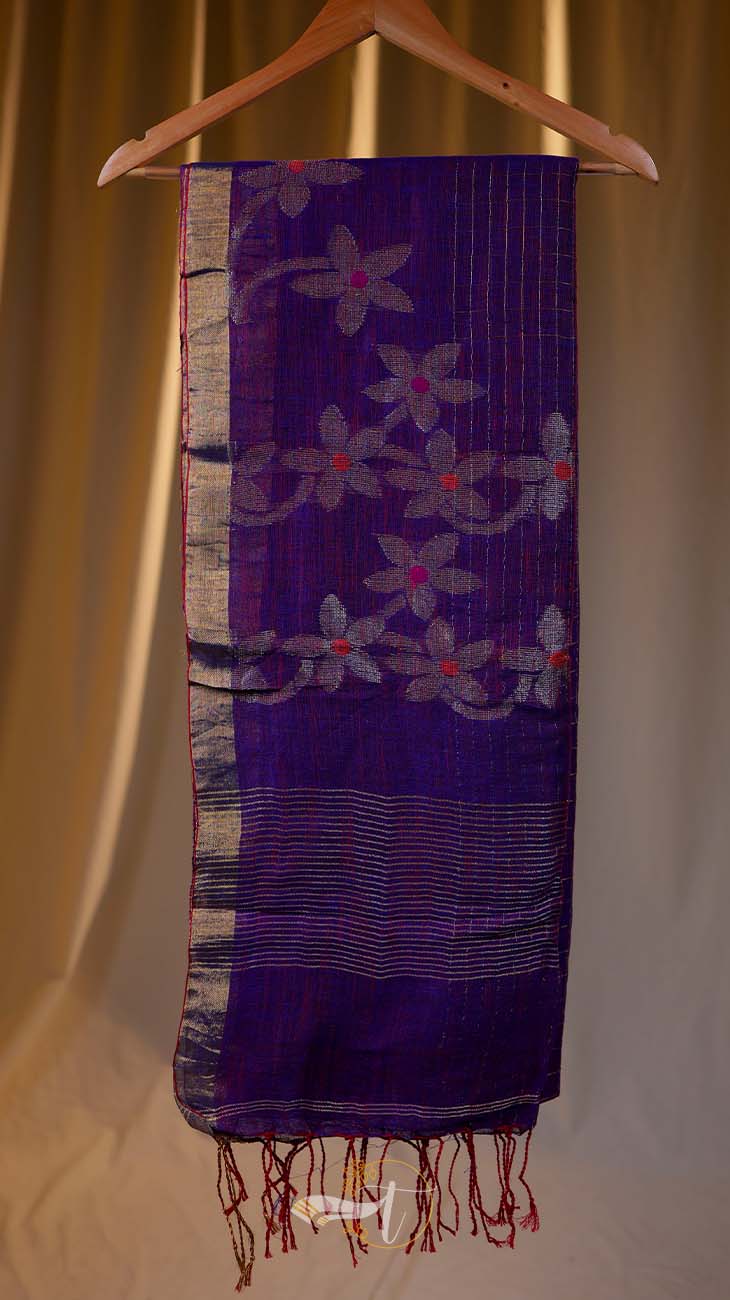 Purple scarf with floral patterns hanging on a wooden hanger against a beige curtain background