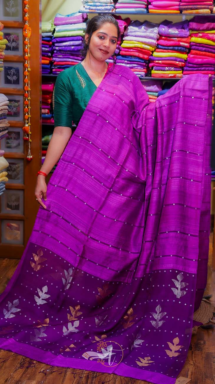 Woman holding a purple saree with a colorful background of fabric