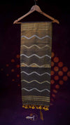 Textile with wavy pattern and yellow tassels on a hanger against a dark background