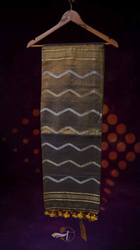 Textile with wavy pattern and yellow tassels on a hanger against a dark background