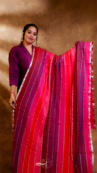 Woman holding a vibrant red and pink saree against a brown background