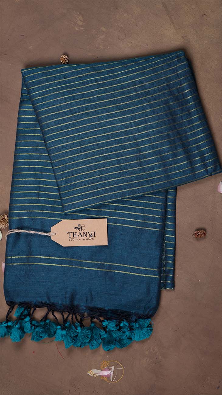 Blue striped towel with tassels on a brown background, featuring a 'THANUKI' tag.