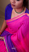 Person wearing a bright pink and purple saree with a blurred background