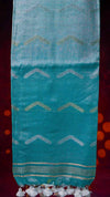 Turquoise fabric with zigzag pattern and tassels on a dark background