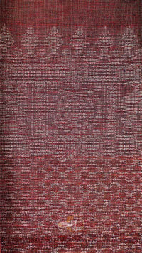 Textured fabric with a subtle pattern in shades of red and brown.
