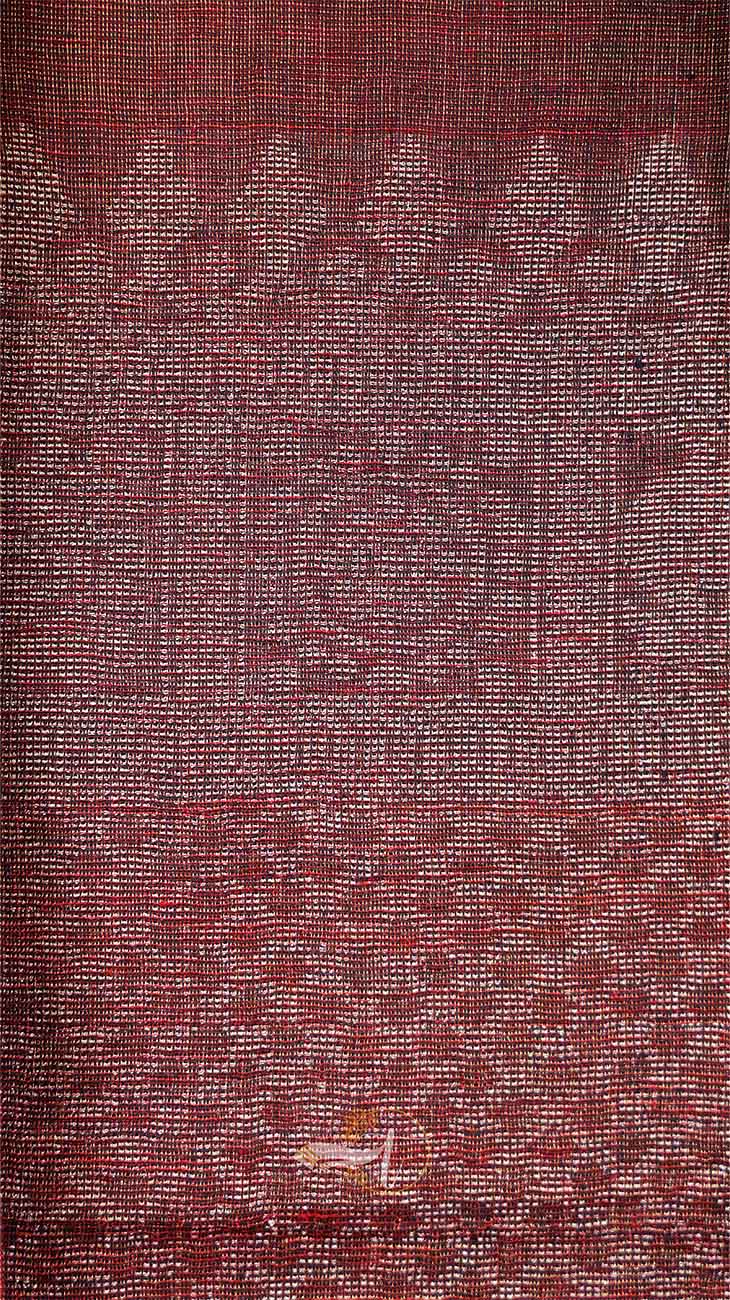 Textured fabric with a subtle pattern in shades of red and brown.