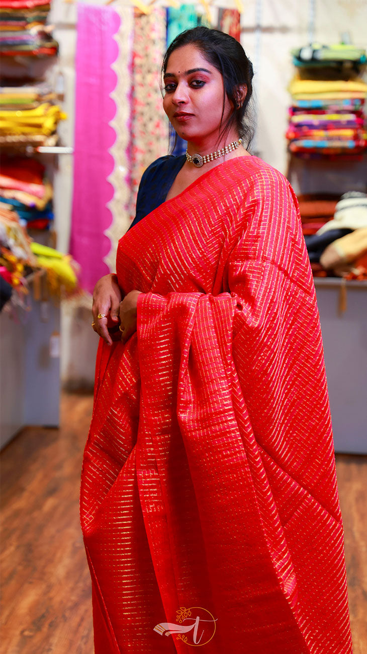 Woman wearing a red saree with a blurred background of a store.