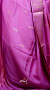 Close-up of a pink fabric with gold patterns and a brand logo.