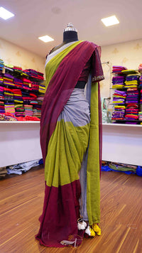 Mannequin wearing a maroon and green saree in a store setting with colorful fabrics in the background.