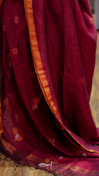 Red saree with gold border and patterns on a wooden floor
