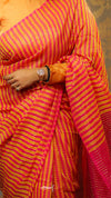 Person wearing a bright pink and orange saree with a textured pattern.