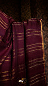 Close-up of purple fabric with gold stripes against a dark background